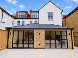 Rear house extension in Esher with brickwork, black-framed glazed doors and a tiled patio