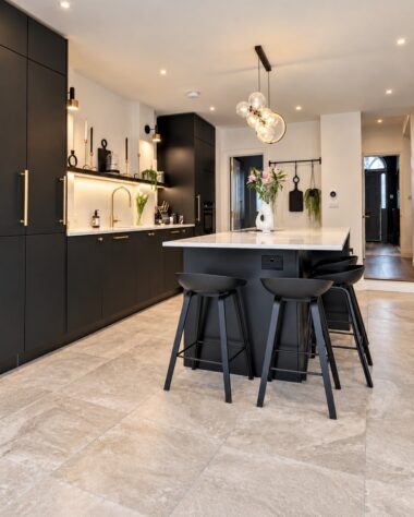 Modern kitchen refurbishment in London with black cabinetry, central island and brass fittings
